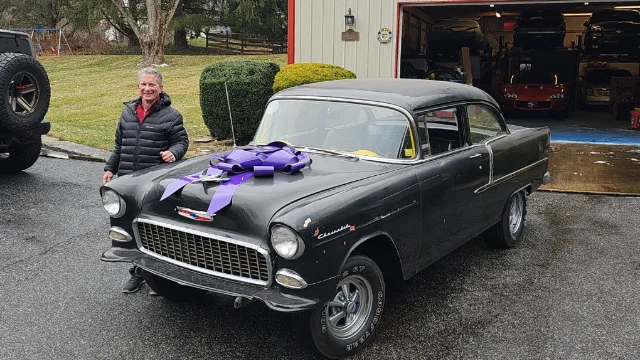 A full restored antique car with a purple bow on top