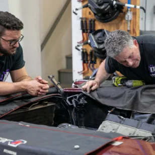 Two mechanics looking under the hood of a car