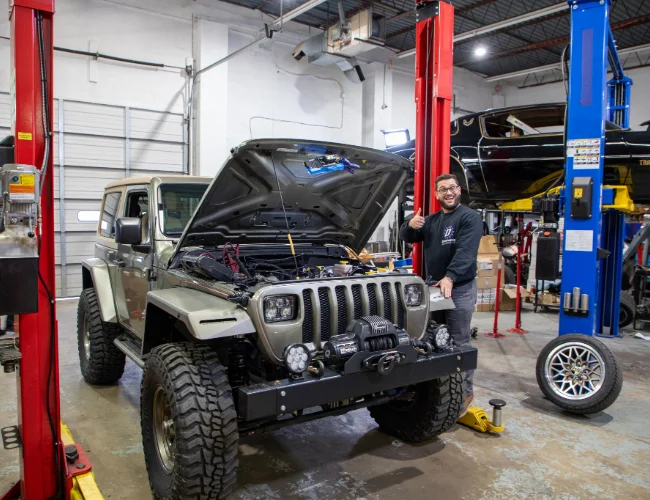 A team member posing next to a brown Jeep YJ